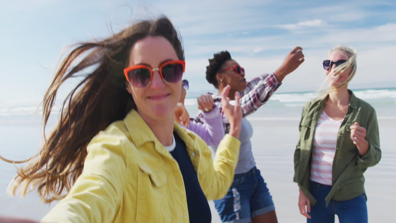 un grupo feliz de amigas diversas divirtiéndose, bailando y sonriendo en la playa