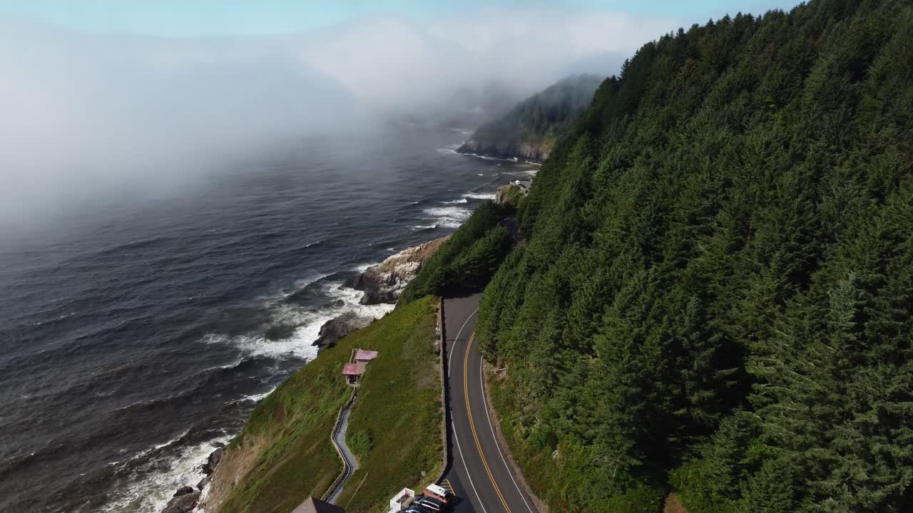 toma de drones en el sentido de las agujas del reloj de autos conduciendo por la carretera con vistas a una impresionante vista al mar en la costa de oregon