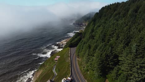 clockwise drone shot of cars driving down the road overlooking a stunning ocean view on the oregon coast