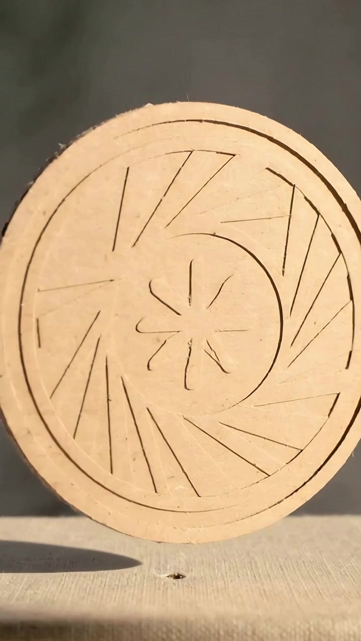 Video verticale: Disco di legno che gira dopo essere stato posizionato su un perno, rivelando un motivo floreale intagliato su una panca