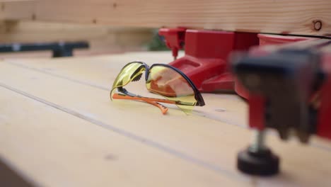 craftsman takes safety glasses from a table