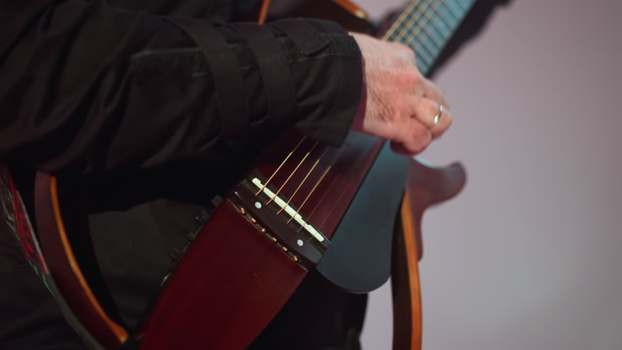 Close-up of a guitarist's hand skillfully playing a red guitar, with a softly blurred grey background enhancing the focus on the musical expression