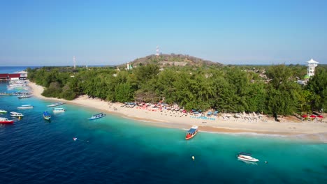 Luftdrohnen-Steigen-Auf-Und-Offenbaren-Den-Sandstrand-Auf-Der-Insel-Gili-Trawangan-Und-Fähren,-Die-An-Einem-Sonnigen-Tag-Entlang-Der-Küste-Angedockt-Sind