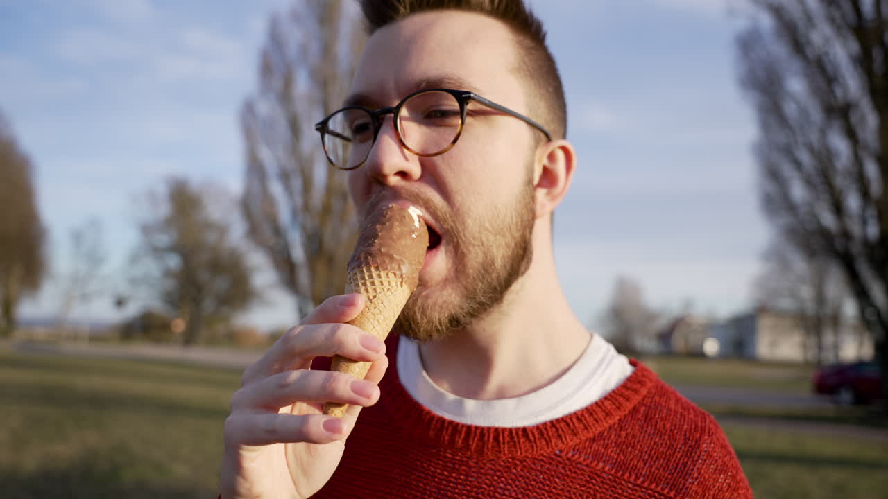 Caucasian European man in glasses eating cold delicious snow ice cream cone dessert hot summer day relaxing tasty vanilla chocolate milk diary frozen protein sugary sugar sweet candy enjoying enjoy