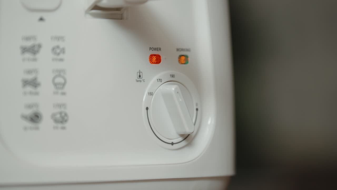 Primo piano di una mano che regola la manopola della temperatura del fornello all'interno.