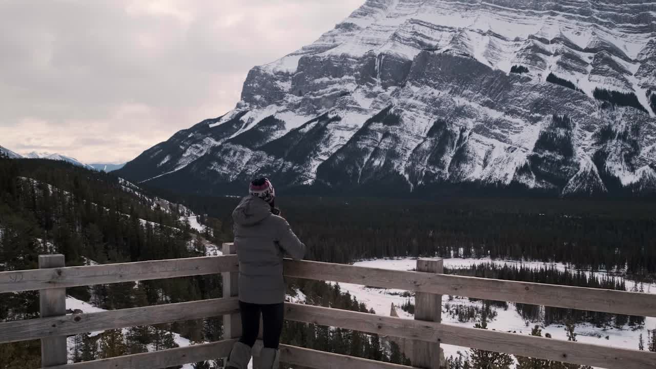 joven excursionista descubriendo un impresionante mirador del monte rundle en banff, alberta, canadá, gran angular de mano inclinado hacia arriba en invierno durante el día afuera