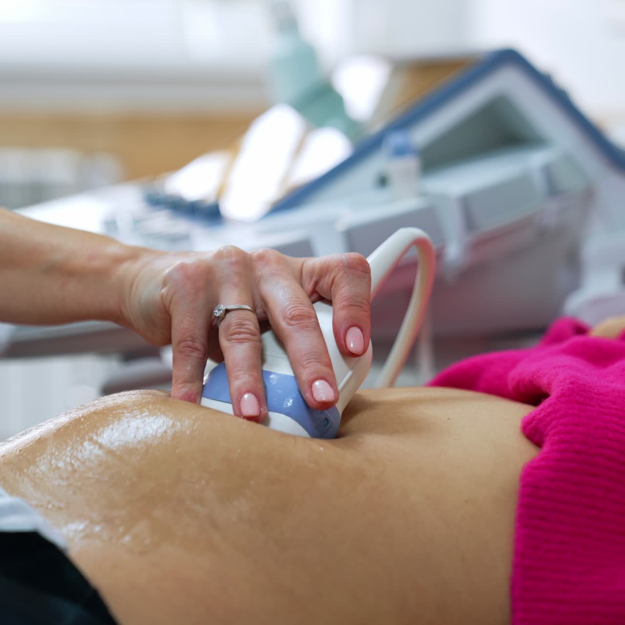 Female doctor's hand moving the ultrasound device by the patient's belly. Ultrasonic pregnancy scanning
