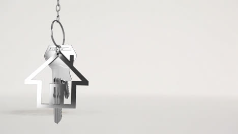 house keys and key fob hanging over 3d house model in the background