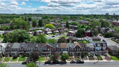 long row of colored houses in small american town at sunny day. spring season in american neighborhood of lancaster, pa. aerial forward wide shot.