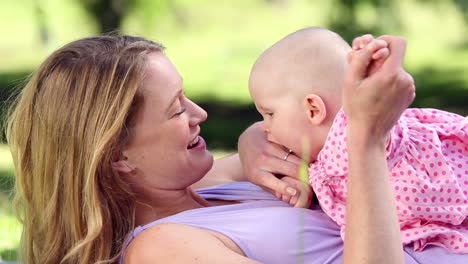 glückliche mutter spielt mit ihrem baby im park