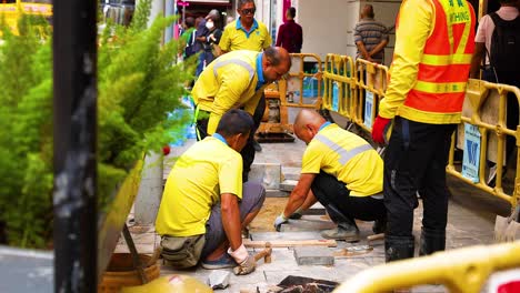 trabajadores reparando acera en una zona urbana ocupada