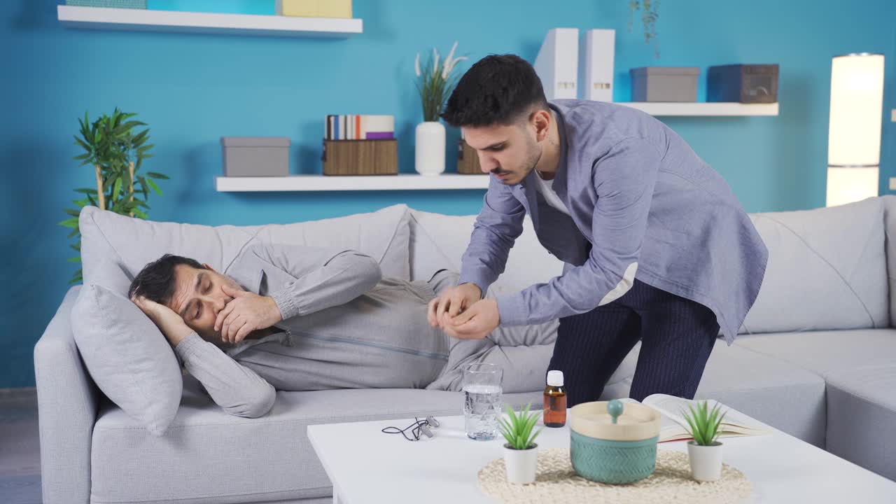 어른이 된 아들이 집에서 아픈 아버지를 돌보고 있습니다.