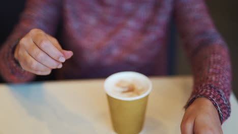 woman adding sugar to her coffee in a fast food restaurant. unhealthy eating and drinks concept