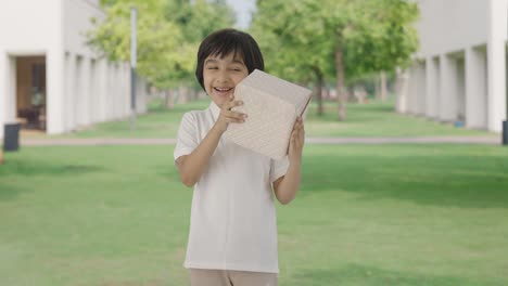 happy indian boy receiving a gift in park