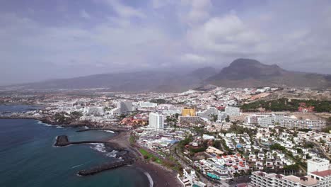 aerial flying backwards of tenerife coast holiday resort city