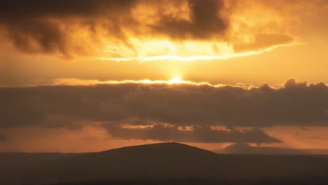 sunrise through clouds and hills