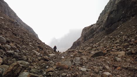 a group of climbers ascending between two pikes among the clouds on a rocky mountains