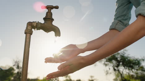 Mujer-Campesina-Lavándose-Las-Manos-Bajo-El-Grifo-En-Una-Granja-Rural-Agua-Dulce-Que-Fluye-Del-Grifo-Con-El-Sol-De-La-Tarde