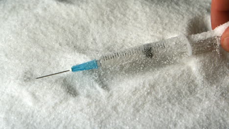 hand taking syringe out of pile of sugar