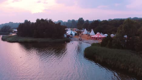 aerial drone flight over lake towards festival area