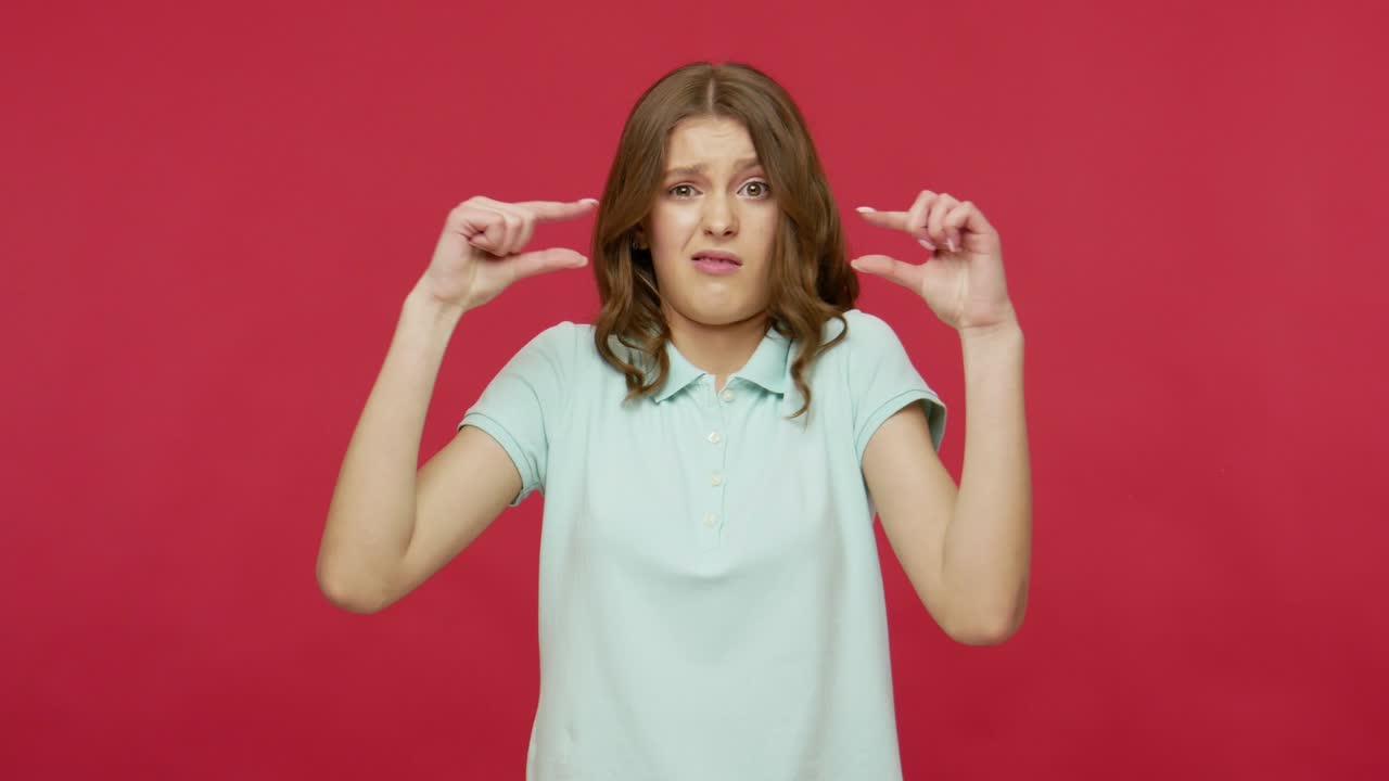 pequeña cantidad, baja calificación. joven mujer morena en camiseta haciendo un pequeño gesto, mostrando pequeño tamaño