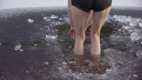 SLOW-MOTION---Beautiful-legs-of-a-young-woman-walking-into-icy-water,-jumps-out