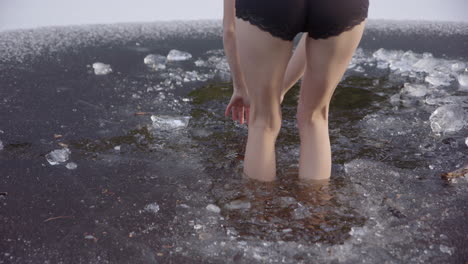 slow motion - beautiful legs of a young woman walking into icy water, jumps out