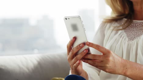mujer joven usando teléfono móvil en la sala de estar en casa