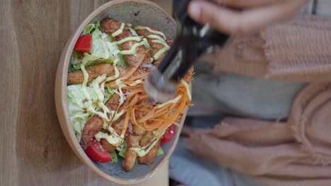 person pouring dressing on a chicken salad