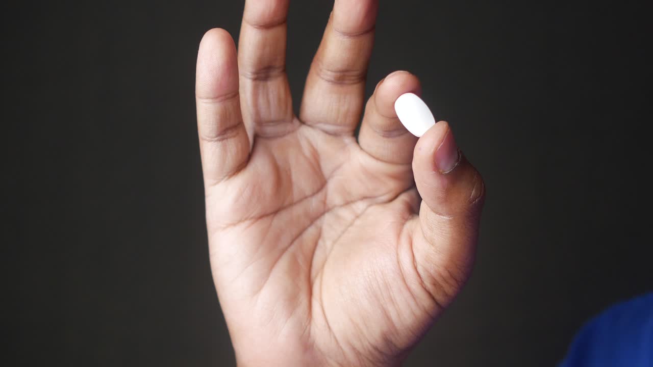 una mano sosteniendo una píldora blanca