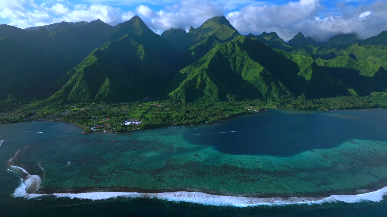Maisema Tahitin satamasta, Teahupo'on surffiaallot, aurinkoinen sininen taivas, Eteläinen Tyynimeri, koralliriutta. Ilmakuva dronella Ranskan Polynesiasta, jossa näkyy tuomaritorni, retkiveneitä, vesiskoottereita, Passe Havea -saari ja ympyränä kohoavat tulivuorenhuiput.