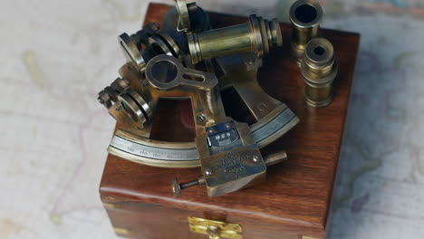 an antique nautical sextand with a rose wood box on a vintage world map