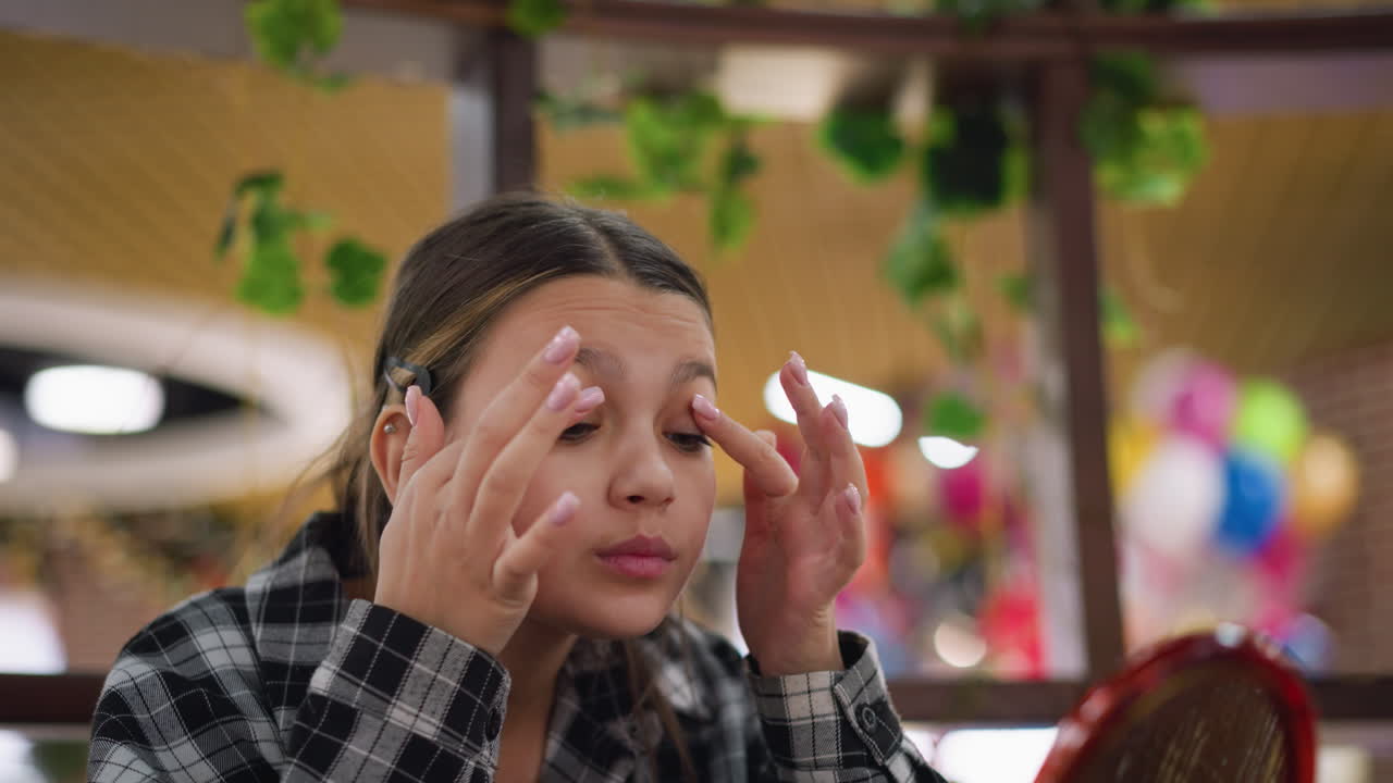 joven aplica cuidadosamente maquillaje alrededor de los ojos usando mezclador de belleza, expresión enfocada, belleza natural, y rutina de cuidado de la piel capturada en iluminación suave, herramientas de belleza y espejo crean estética