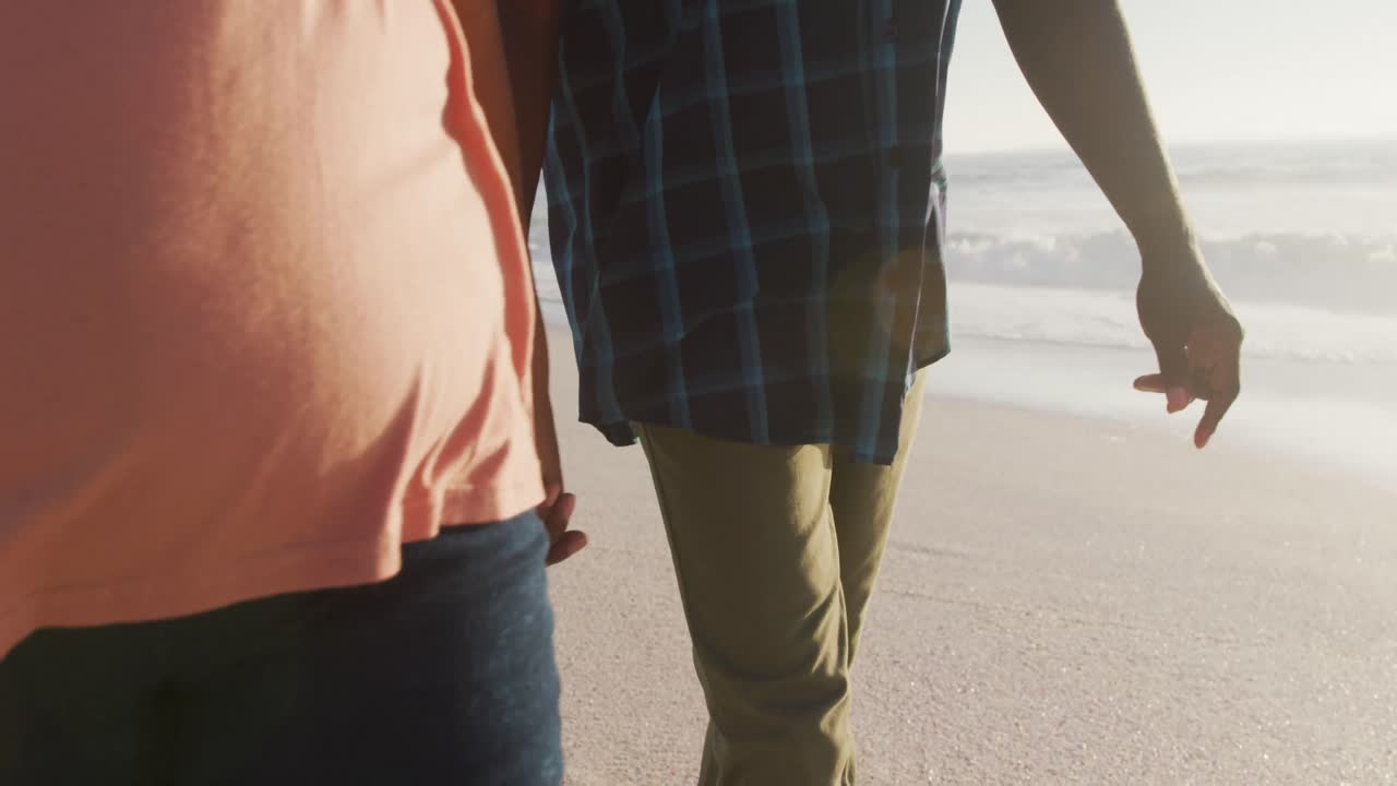 아프리카계 미국인 부부가 손을 잡고  ⁇ 은 해변에서  ⁇ 고 있습니다.