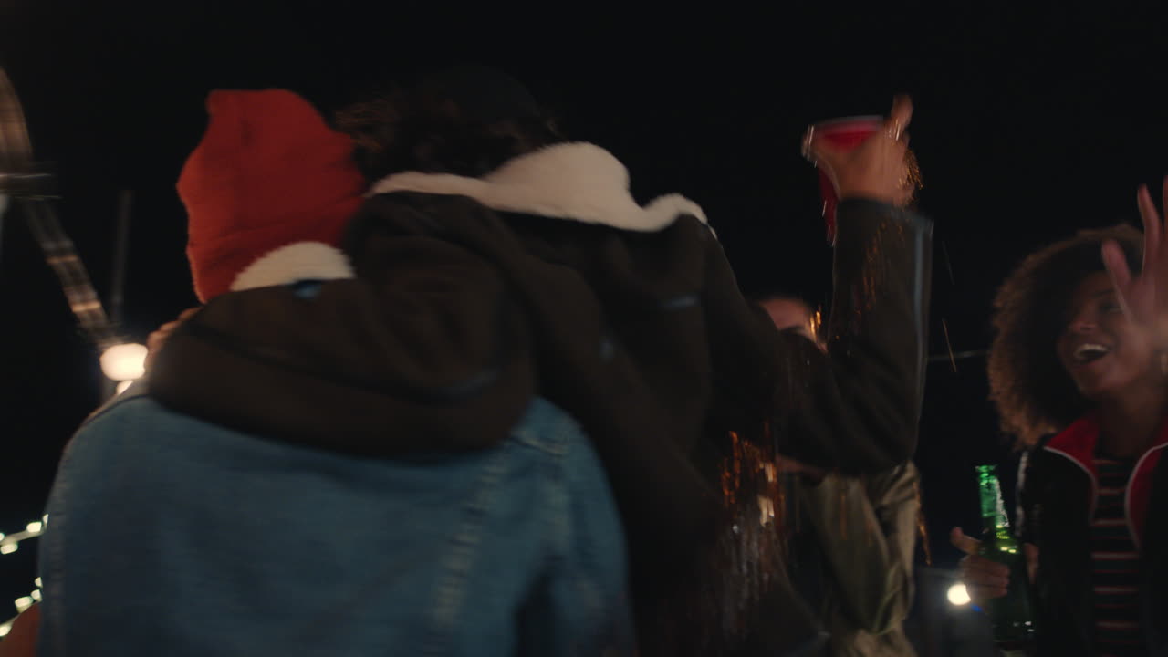 молодые друзья весело танцуют вместе, наслаждаются вечеринкой на крыше, смеются, празднуют дружбу.