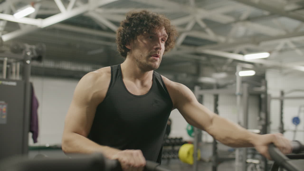 Muscular Athlete Doing Intense Air Bike Workout at Gym