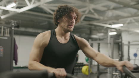 muscular athlete doing intense air bike workout at gym