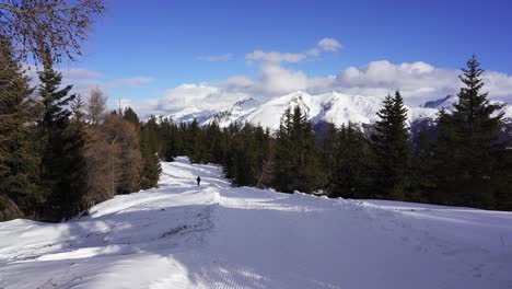 Lonely-hiker-walks-into-the-distance-through-a-deserted-winter-landscape-in-the-snowy-mountains