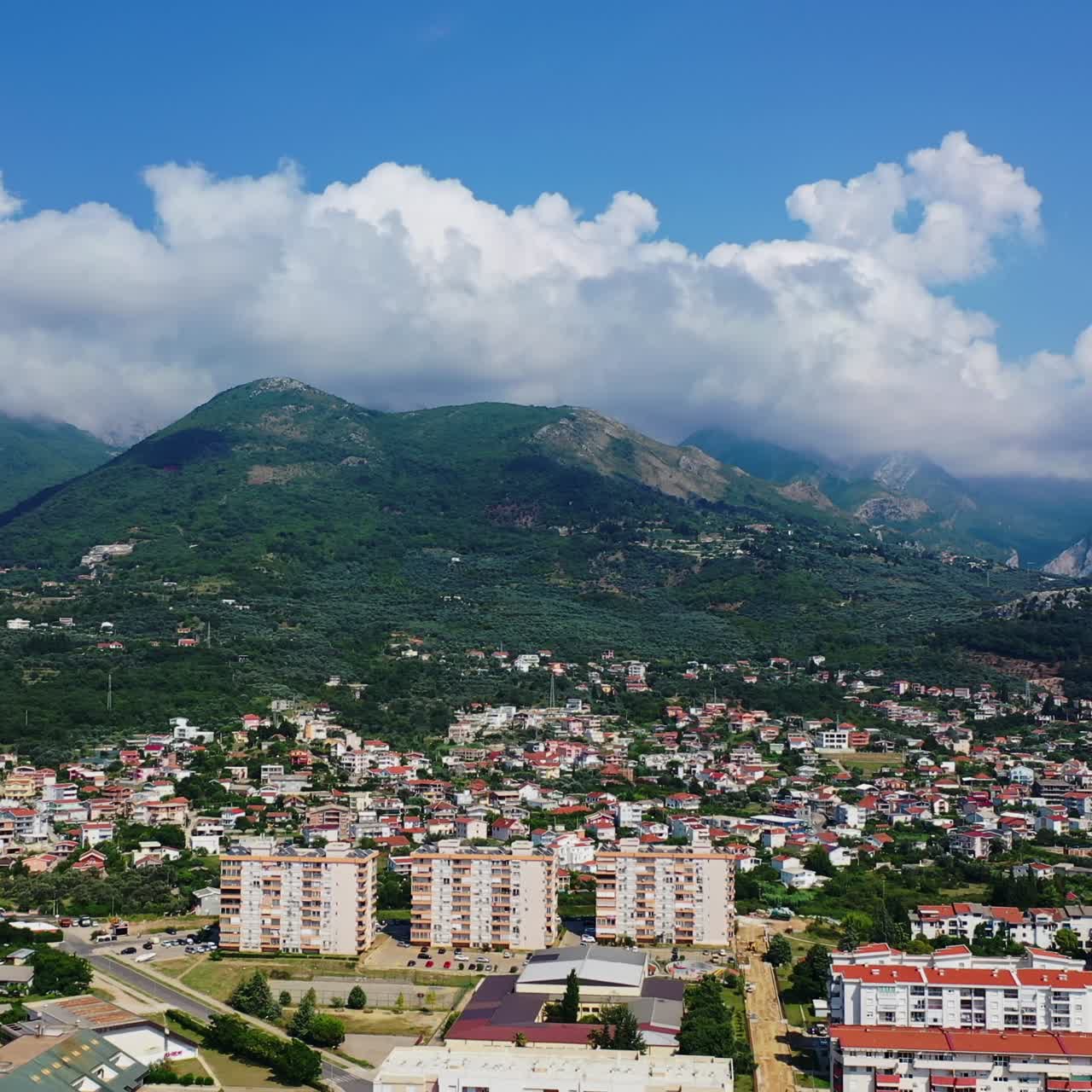 Vista della città di Bar, disseminata ai piedi di verdi montagne in Montenegro. Un cielo di nuvole bianche si raccoglie sulle cime di splendide rocce.