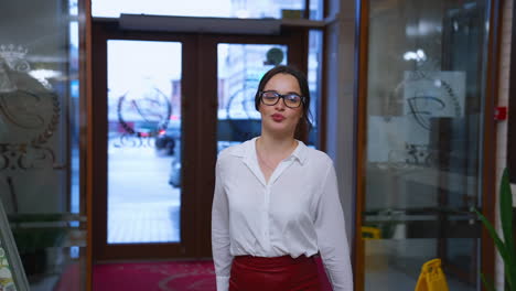 confident young woman in a luxury hotel. stylish girl coming into a hotel and moving to the reception desk. charming lady in glasses indoors.
