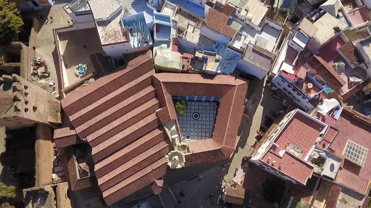 Stunning HD top-down aerial of Chefchaouen's medina, showcasing traditional inner courtyards with mosaic tiles and blue fountains. Captures the unique architecture of Morocco's Blue Pearl