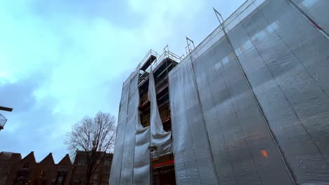 Building-reconstruction-covered-in-white-blankets-blowing-in-a-stormy-wind