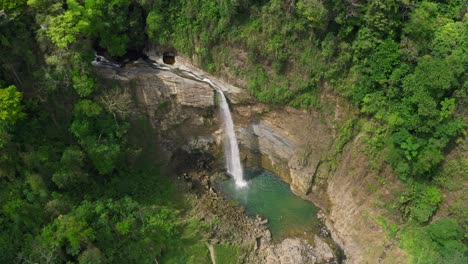 Stunning-tropical-waterfall-dropping-down-rock-cliff-in-rainforest-landscape