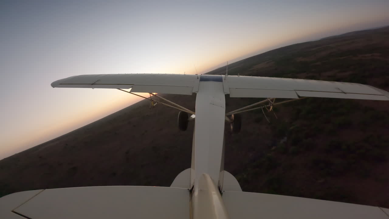 Aereo leggero che sorvola la savana arbustiva al tramonto