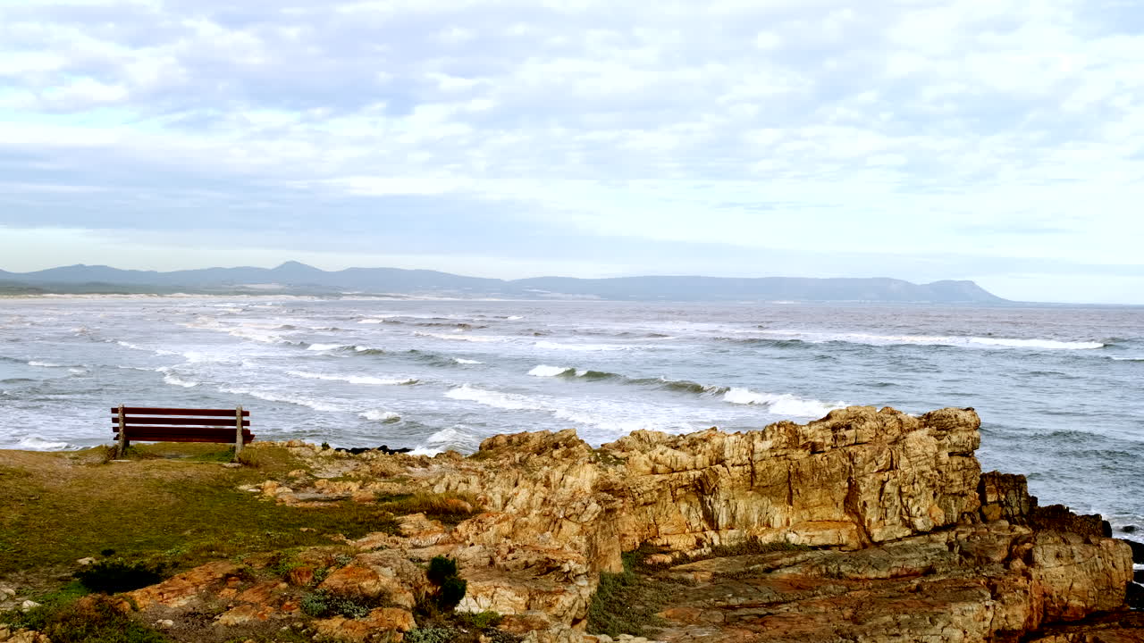en el banco de la costa de hermanus en el punto de vista de la bahía de walker mientras las olas rodan
