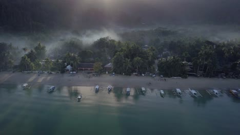 Aerial-of-misty-morning-in-beautiful-fishing-village-by-the-beach-in-the-Philippines---camera-pedestal-down