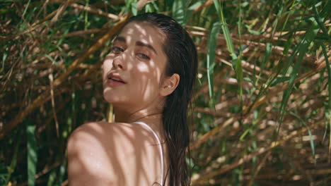 gentle woman standing sunlight bamboo closeup. long-haired lady looking camera