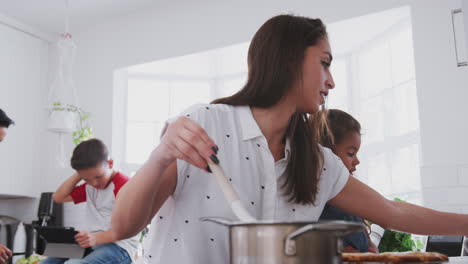 mother and young daughter preparing food in the kitchen, dad and pre-teen son in the background