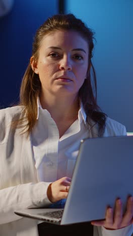 vertical video: tired manager raising head looking at camera sighing holding laptop