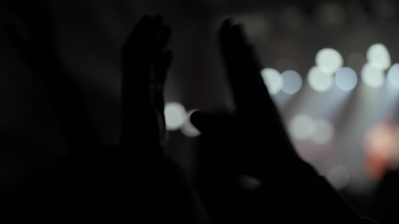 Silhouettes of Audience Clapping Hands at Live Music Concert